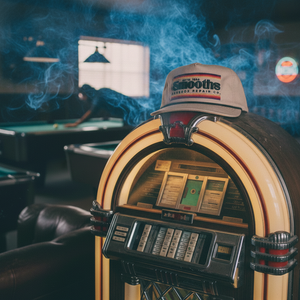 Vintage jukebox with a cap on top in a smoky bar setting